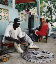 Haitian artist carving an oil drum